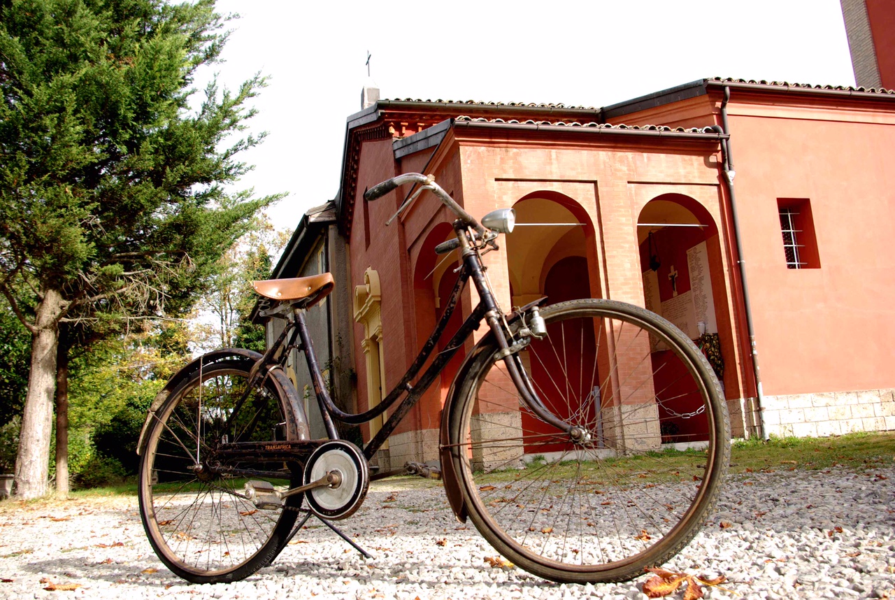 09 La biciletta di don Giovanni Fornasini e sullo sfondo la chiesa di Sperticano foto Franci